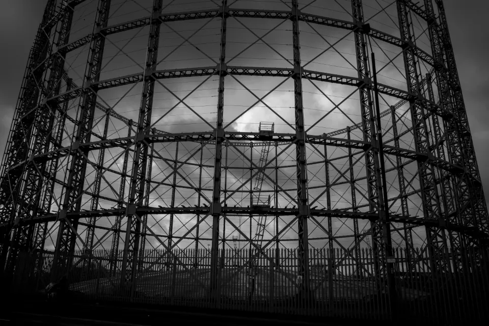 The steel frame of a disused gasholder against a dark sky